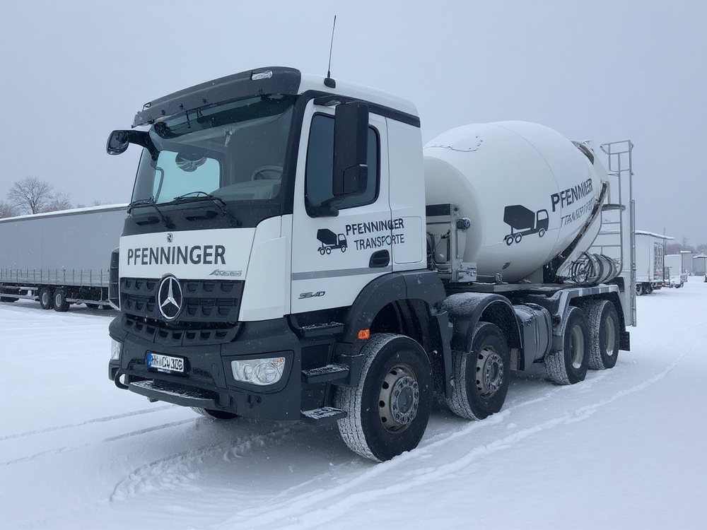 Pfenninger-Fahrmischer steht auf einem verschneiten Abstellplatz, im Hintergrund geparkte Auflieger